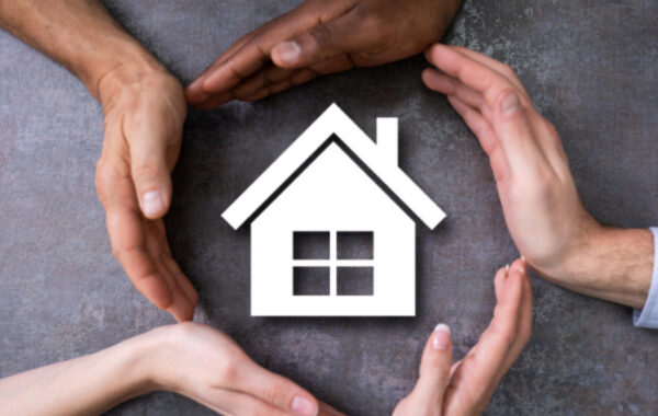 Photo of five hands circled around a graphical image of a house