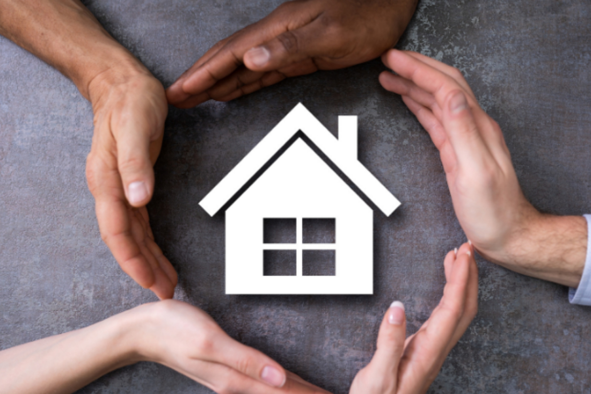 Photo of five hands circled around a graphical image of a house