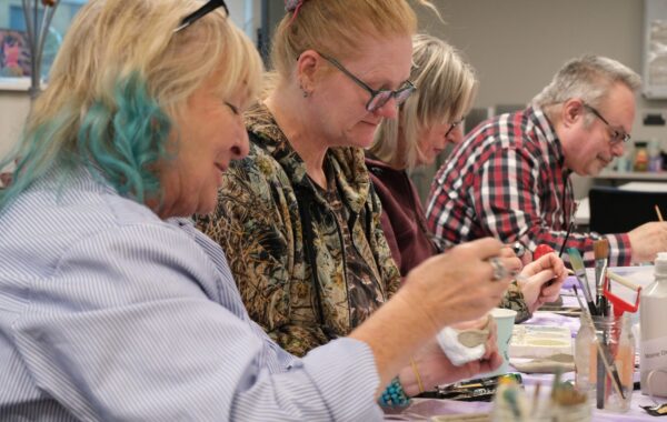 Peer tutor and recovery college students engage in a pottery workshop.