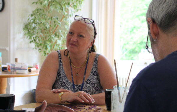 Southdown client is in a craft workshop. They are smiling and looking across to somebody on the table with them.