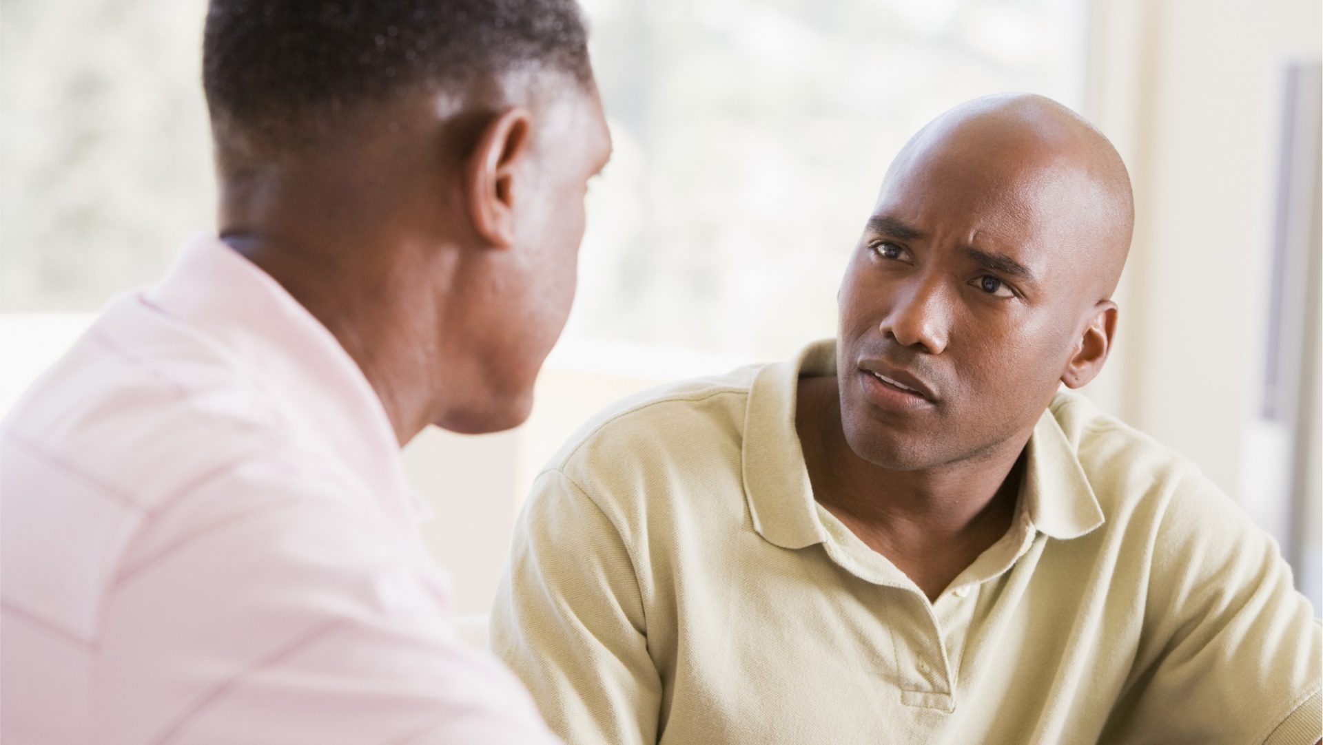 Close up head and shoulder shot of two seated people facing each other in conversation and dressed informally