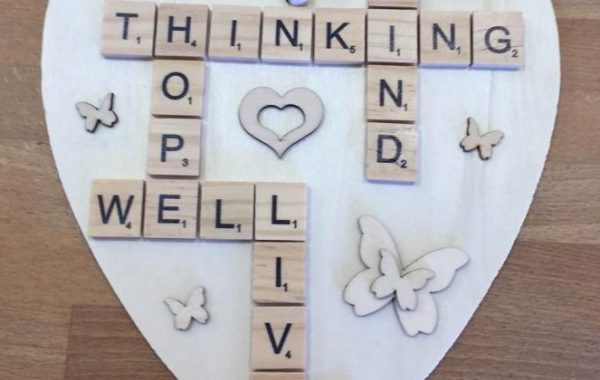 Close up photo of a wooden heart with scrabble letters including Thinking Well