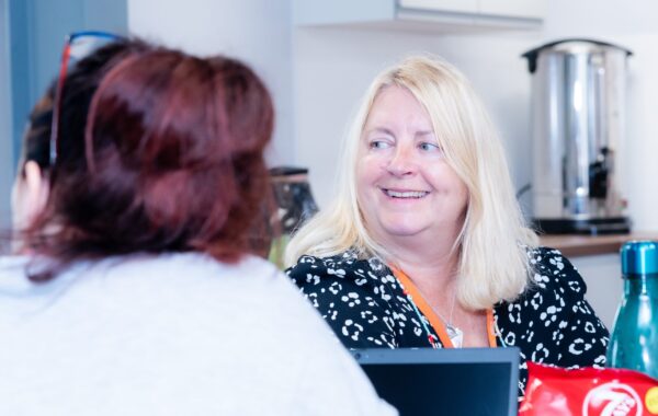 Two people having a friendly conversation in a bright, relaxed setting, reflecting the supportive and understanding approach of the Thinking Well mental health service.