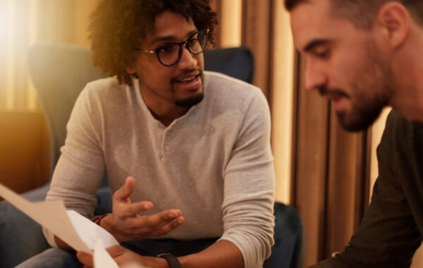 Close up photo of two people say talking, one looking reflective