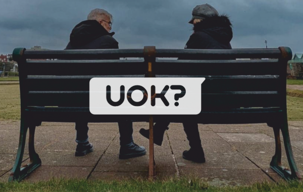 Two people sat on Brighton seafront bench looking at each other
