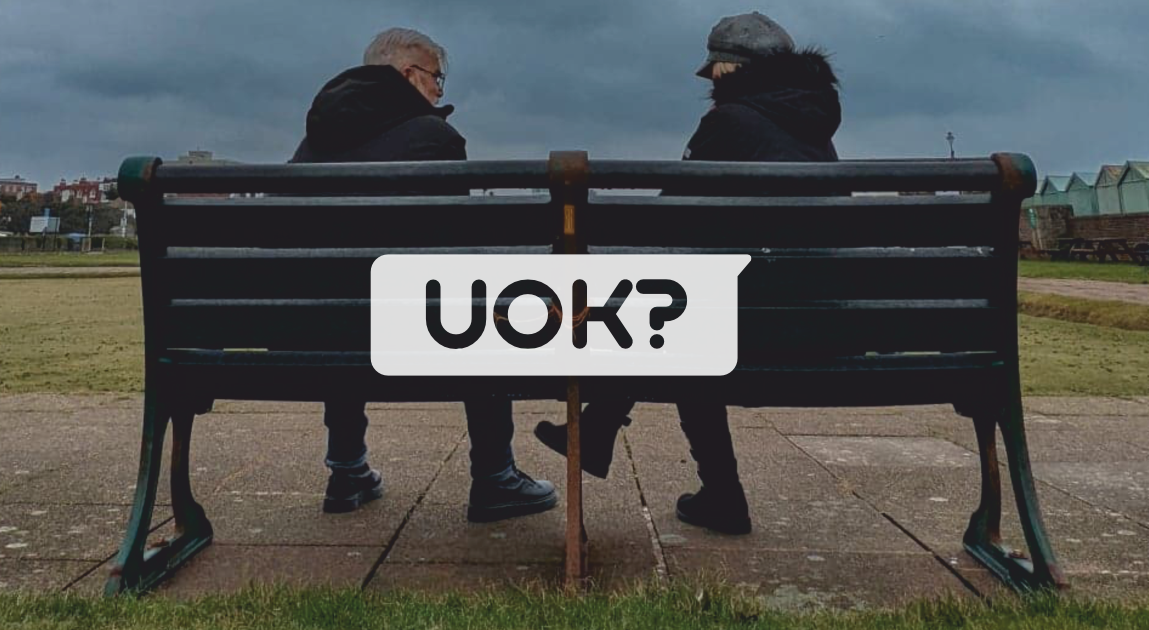 Two people sat on Brighton seafront bench looking at each other