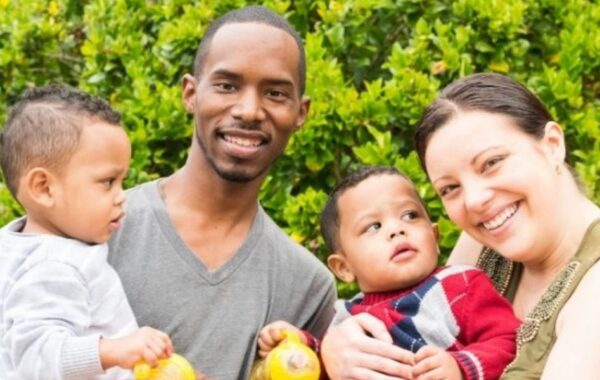 Photo representing family of four - two adults holding two young children