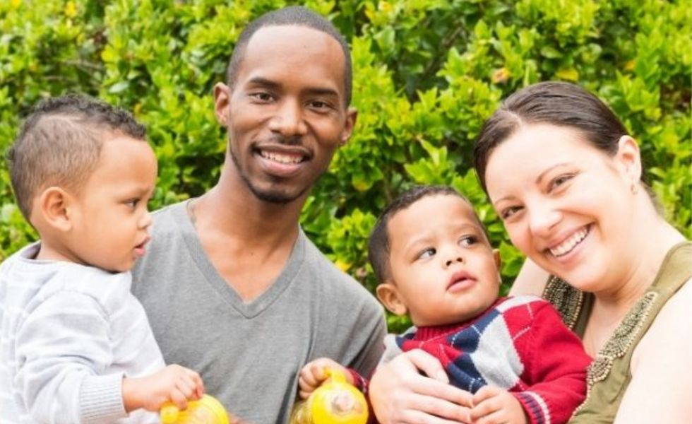 Photo representing family of four - two adults holding two young children