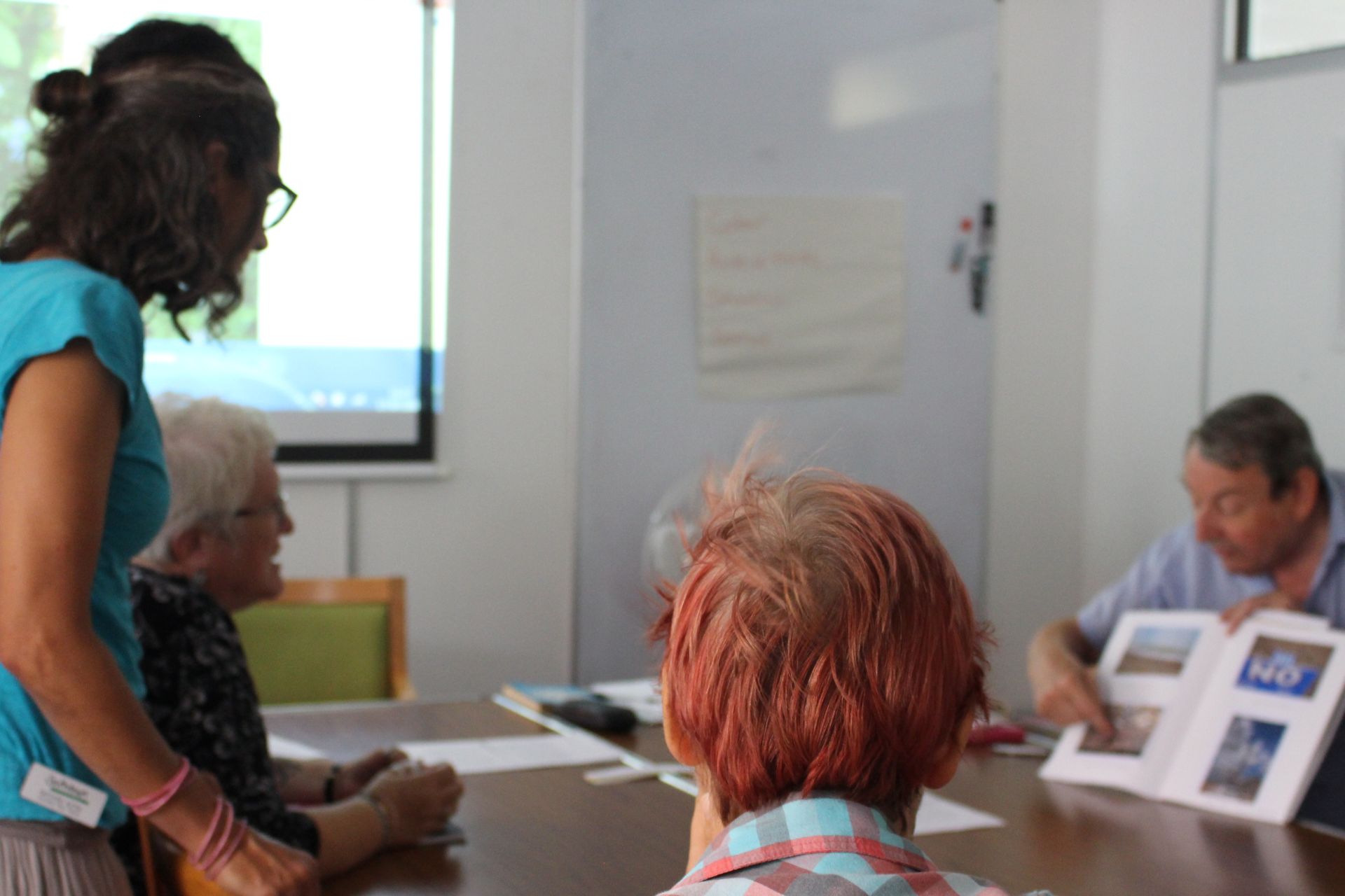 Photo of group of students and tutor around a table with one student showing an album of photos to the others