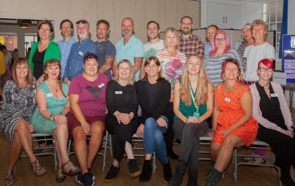 Group photo of Recovery College staff and volunteers sitting and standing and smiling