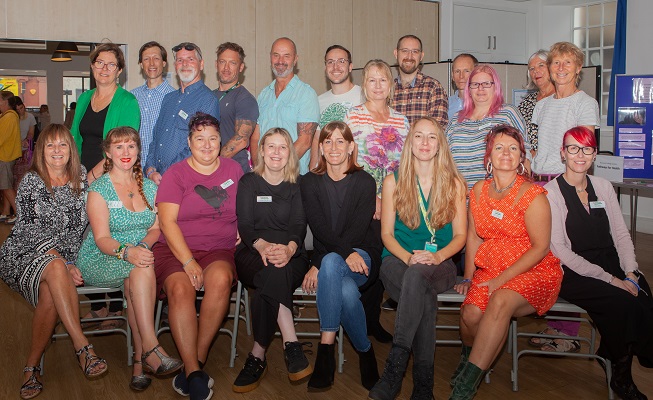 Group photo of Recovery College staff and volunteers sitting and standing and smiling