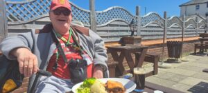 A man sits in a pub garden with his lunch on his plate