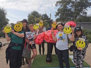 A group of people are standing with masks next to a large Shaun the Sheep sculpture