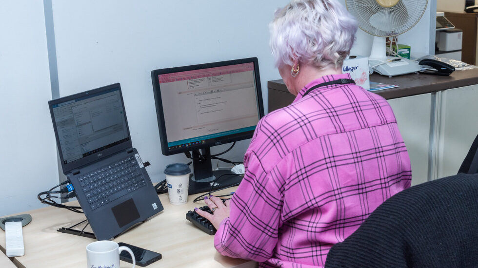 A Southdown colleague is sat at a desk looking at two computer screens in front of them.