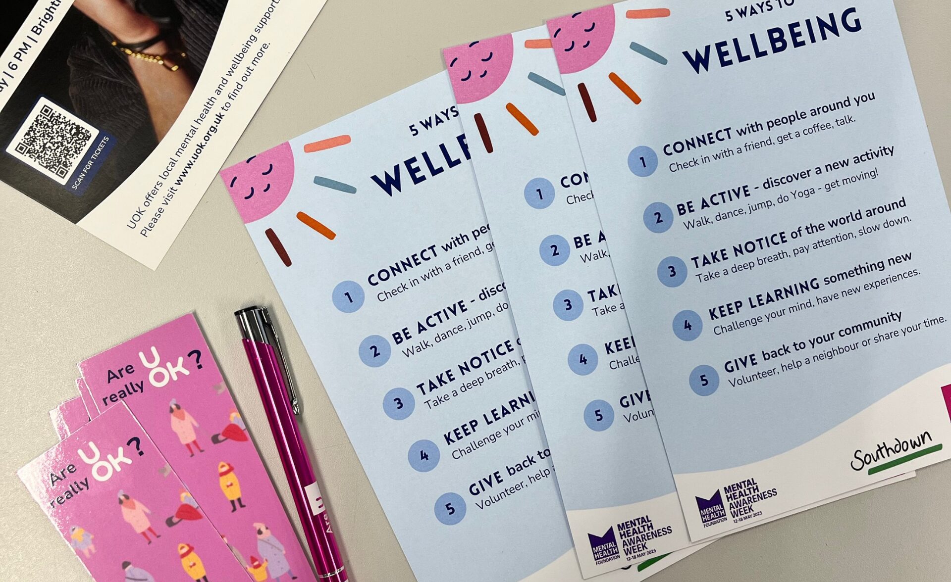 Promotional materials from the UOK event for Mental Health Awareness Week, including wellbeing tip cards, UOK leaflets, pens, mints, and bookmarks encouraging mental health check-ins.