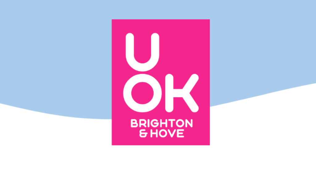 UOK Brighton and Hove logo in a white font, on a bright pink rectangle which is a brand pink. in the background is a light blue and white wavy background.