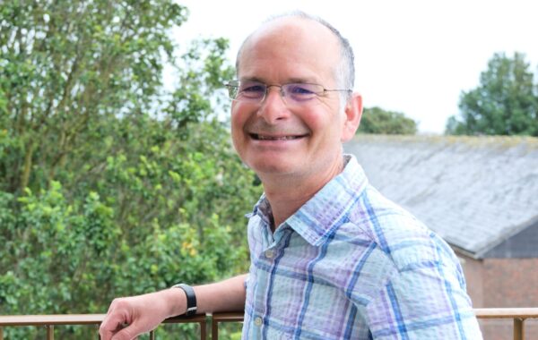 Jonathan Senker, Southdown’s incoming Chair, smiles beside an outdoor railing, with trees and a building in the background.