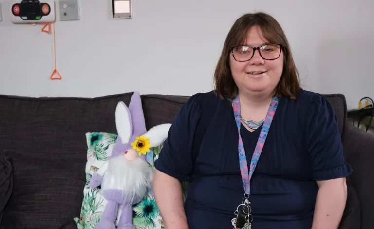A woman with glasses sits on a sofa in a relaxed setting
